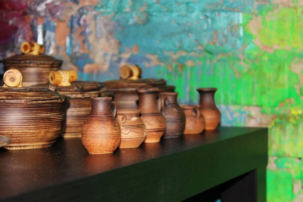 Many small clay jugs and pots standing on a green table. — Stock Photo, Image