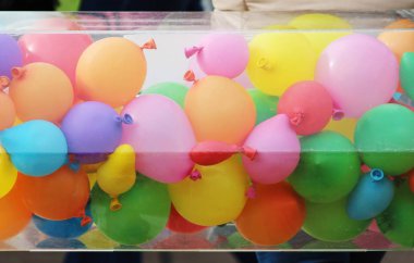 Bir sokak festivalinde plastik bir kutuda çok renkli balonlar.