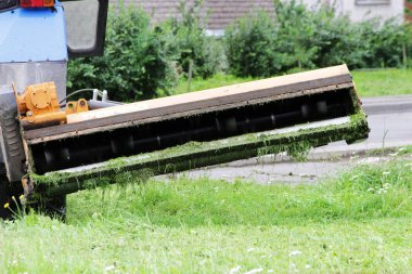 Şehrin kentsel bölgesinde çim biçmek için traktör kullanılıyor.