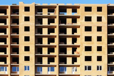 Parlak güneşli bir günde mavi gökyüzünün arka planında bitmemiş tuğla ev