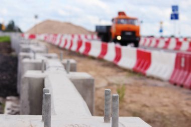 Beton bariyerler ve yol kenarında kırmızı ve beyaz plastiklerin durduğu viyadük kavşağında yol kavşağı inşaatı