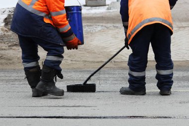 Tulum iki yol işçileri ile sıcak asfalt yol şerit kenarında yolun tamirinde dökülür