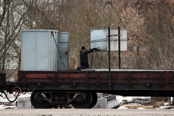 Працівник контролює потік палива з резервуара, який підвішений за допомогою залізничного крана — стокове фото