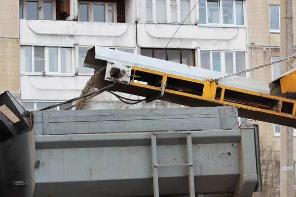 A yellow city sweeper cleans the road from dirt that enters the body by the conveyor — Stock Photo, Image