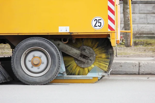 Barredora urbana amarilla limpia la carretera de la suciedad con un cepillo redondo en la primavera . — Foto de Stock