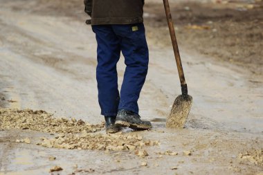 Bir işçi bir kürek ile çakıl yol seviyeye çukurlara strews
