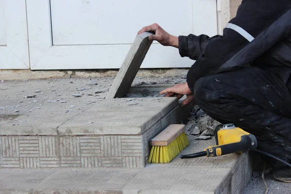 Professionele bouwvakker stenen tegels te leggen op de veranda bij de ingang van de winkel. — Stockfoto