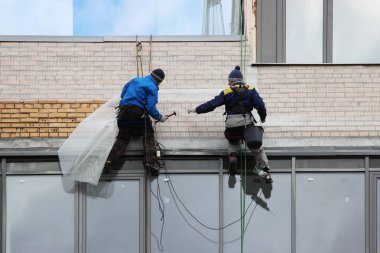 Endüstriyel dağcılar bir bina mesh yüksek bir binanın duvarında düzeltmek.