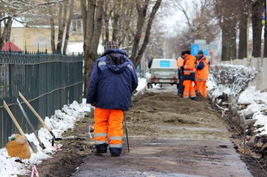 Çalışan taş ustaları kaldırımı tamir eder, yol için asfaltlama yapmadan önce kaldırımları kurar.