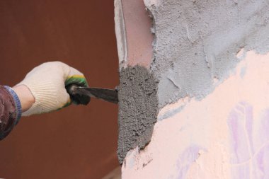 İnşaat işçisi duvarları sıva malzemeleriyle dekore eden bir apartman işçisi. Sıvacı eski evin dış duvarlarını yeniliyor. İnşaat bitirme işleri