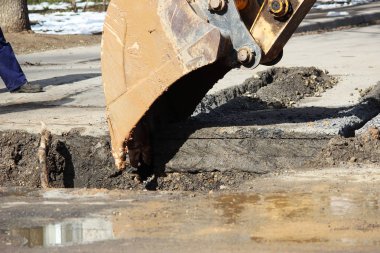 Yer altındaki kazaları elerken yol yüzeyini açmak. Özel eklentisi olan bir traktör ve kovası olan bir kazıcı.