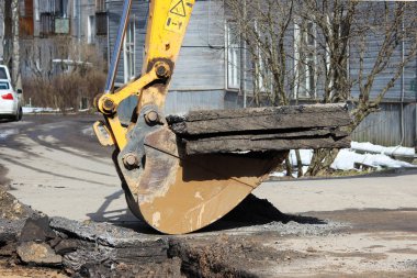 Yer altındaki kazaları elerken yol yüzeyini açmak. Özel eklentisi olan bir traktör ve kovası olan bir kazıcı.