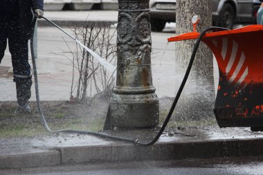 İlkbaharda yüksek basınçlı çamaşır makinesiyle şehir postasındaki kirli direği temizlemek.
