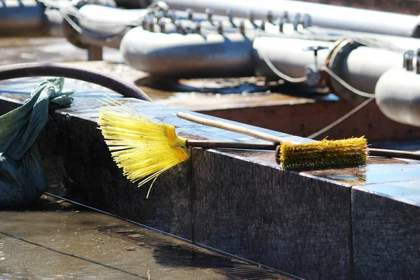 Tools for washing and cleaning the fountain tank lie on the edge, broom and brush