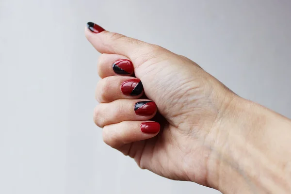 beauty delicate red black manicure with gel varnish on a white wall background