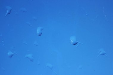 Camdaki yağmur damlaları ve bulanık mavi gökyüzü