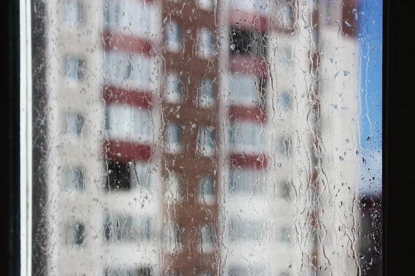 玻璃上的雨滴和模糊的蓝天和房子 — 图库照片