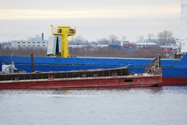 Blue cargo ship and barge with cargo on the river Severnaya Dvina