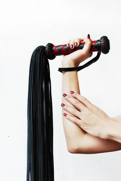 The handle of a red and black lash in a female hand on a white background. — Stock Photo, Image