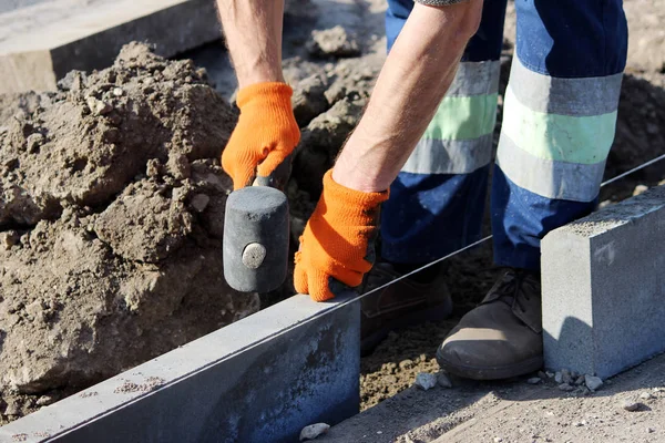 Reparation av trottoaren. Professionell arbetande frimurare i overaller låg trottoarkanter innan du lägger sten stenbeläggningen plattor. — Stockfoto