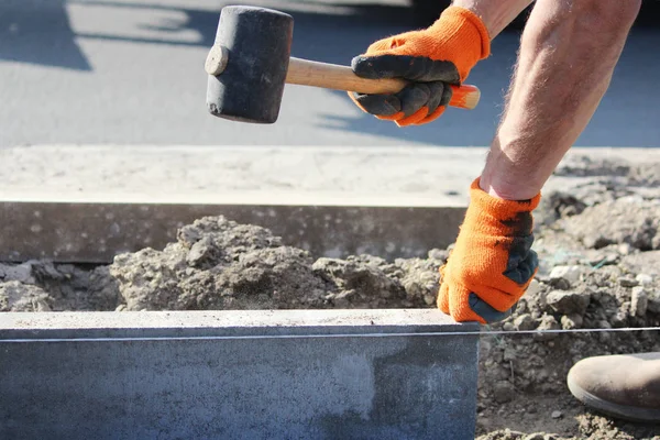 Reparación de la acera. masones de trabajo profesional en overoles poner bordillos antes de colocar losas de pavimentación de piedra . — Foto de Stock