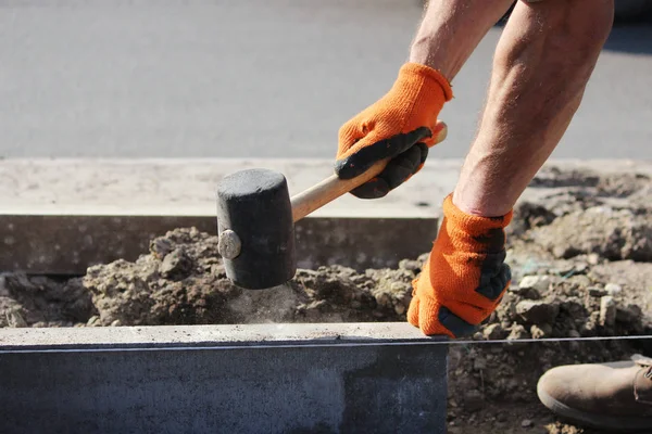 Réparation du trottoir. Les maçons professionnels en salopette posent des bordures avant de poser des dalles de pavage de pierre . — Photo