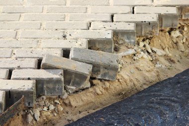 Daha önce döşenmiş kaldırım levhalarının söküldüğü bir ticaret kompleksinde toprak fışkırması.