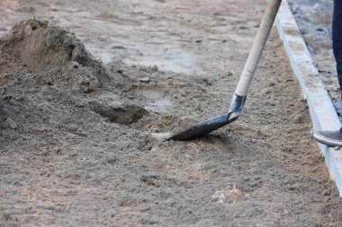 Duvarcılar döşeme taşları için temel hazırlıyorlar, küreklere kum atıyorlar..