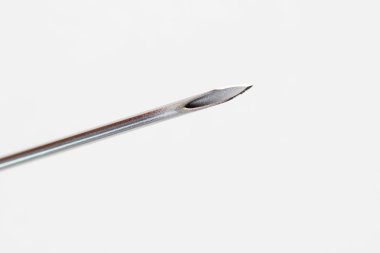 Beyaz arka plandaki bir şırınganın tıbbi iğnesinin makro görüntüsü.