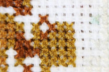 Makro çekim parça nakış deseni kahverengi iplik el yapımı nakış, beyaz kumaş üzerinde çapraz dikiş biçimi.
