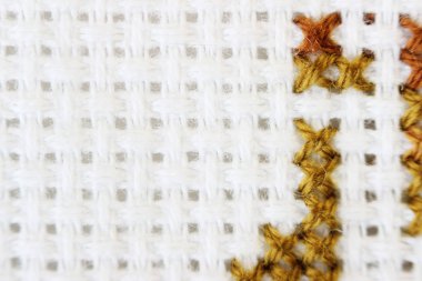 Makro çekim parça nakış deseni kahverengi iplik el yapımı nakış, beyaz kumaş üzerinde çapraz dikiş biçimi.