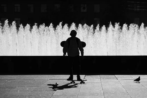 SAINT-PETERSBURG, RUSSIA. Black silhouette of a boy on a skateboard near Complex of singing fountains at Moscow Square in sunny day. — Stock Photo, Image