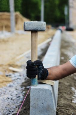 İşçi mason bir çekiç ile kaldırım kaldırıma otobüsler için park inşaatı sırasında atıldı gösterir.