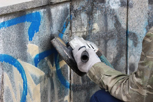 Removal of graffiti on a concrete wall of an underground passage with the help of a angle grinder