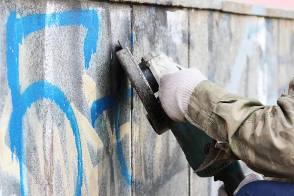 Removal of graffiti on a concrete wall of an underground passage with the help of a angle grinder