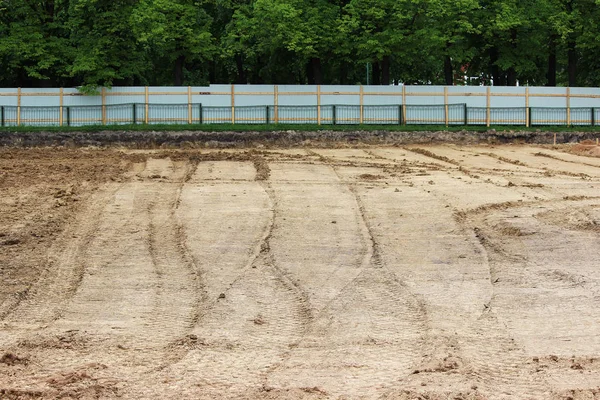 Wiel tracks in de modder, detail voetafdrukken asfalt compactor in de bouw op de bouwplaats van het stadion. — Stockfoto