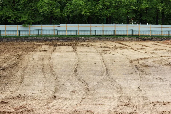 Wheel tracks in the mud, detail footprints asphalt compactor in the construction on the stadium construction site.