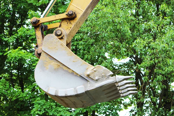 Escavadora de balde contra um contexto de folhagem verde de uma árvore . — Fotografia de Stock