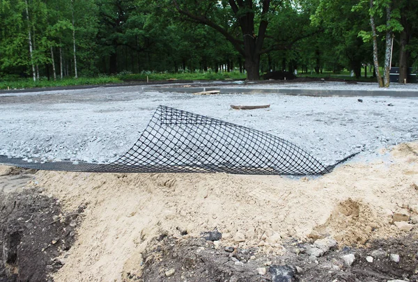 De bouw van de Parking voor bussen, leggen van geomesh op bodem voordat de asfalt stoep, Rusland — Stockfoto