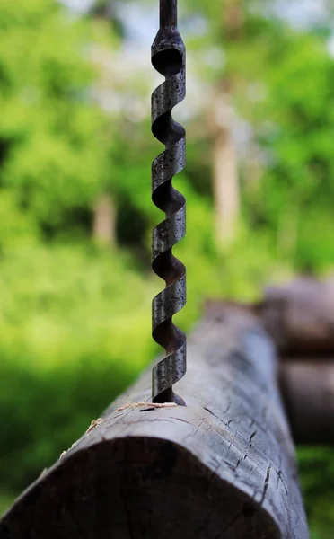 Trapano a spirale in metallo per realizzare fori nei tronchi quando si assembla una struttura in legno e si costruisce una casa — Foto Stock