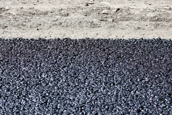Tekstura świeży gorący czarny asfalt kładzie się na nowe drogi w pobliżu drogach — Zdjęcie stockowe