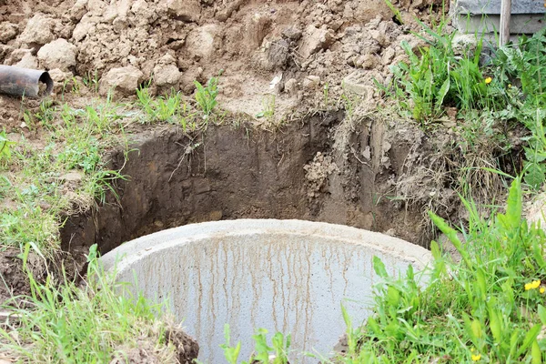 Добре для видобутку води. Будівництво сільського колодязя для видобутку води за допомогою декількох бетонних кілець, покладених у яму землі — стокове фото