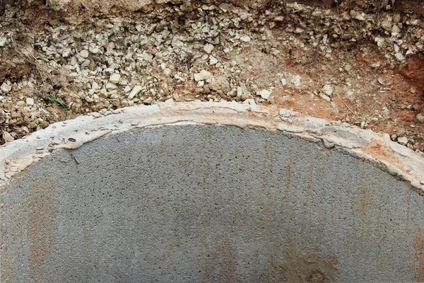 Puits d'extraction d'eau. La construction d'un puits de village pour l'extraction de l'eau à l'aide de plusieurs anneaux de béton posés dans une fosse de terre — Photo