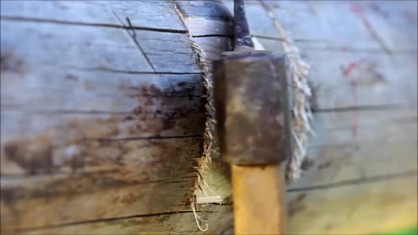 Herstellung einer Rille im Balken zur Fixierung der Verzögerung, auf die der Boden mit einem Beil manuell geplant ist, Russland. — Stockvideo