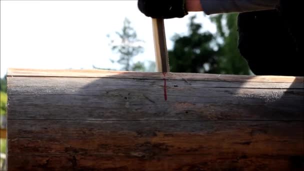 Le travailleur recueille le cadre et perce un trou dans une bûche pour la cheville à l'aide d'une perceuse lors de la construction d'une maison en bois .