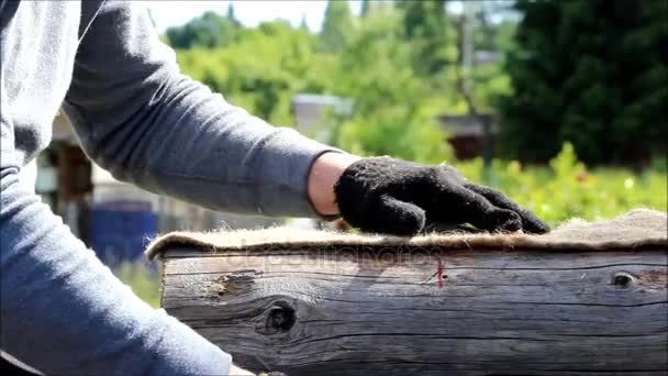 Arbeiter schneidet Liner Dichtung von einer Rolle für die Verlegung zwischen dem Balken, wenn der Bau eines Hauses sind bereit für die Arbeit — Stockvideo