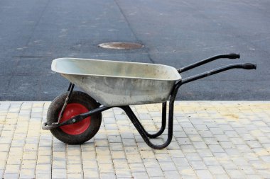 İnşaat sırasında turist otobüsleri için asfalt otoparkın yanındaki kaldırımda boş bir el arabası duruyor.