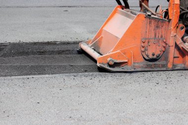 Hortumlu bir traktör yolu onarıyor. Çukurlara yama onarımı.