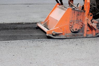 Hortumlu bir traktör yolu onarıyor. Çukurlara yama onarımı.