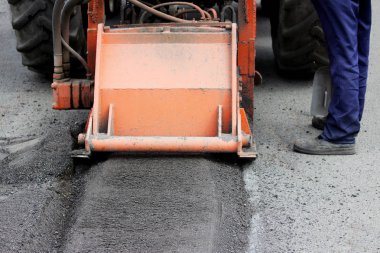 Hortumlu bir traktör yolu onarıyor. Çukurlara yama onarımı.